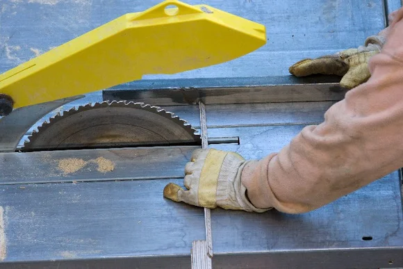 Person sägt Holz mit Tischkreissäge